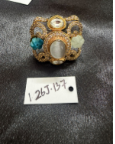 A screenshot of a Google Sheets spreadsheet listing multiple jewelry items for sale, showing photos of ornate brooches with handwritten-style product numbers and prices in a table format.